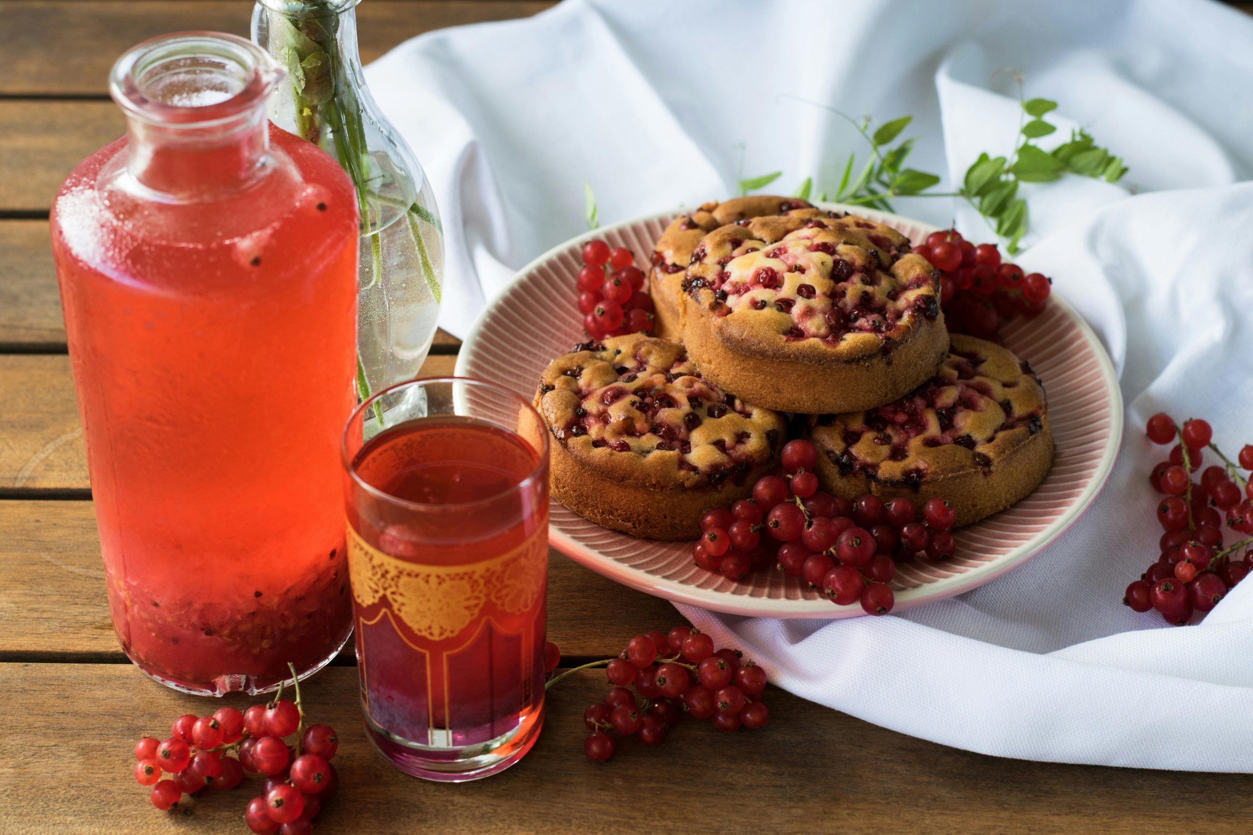 A delicious arrangement of redcurrant muffins with a refreshing red drink, perfect for a summer brunch.